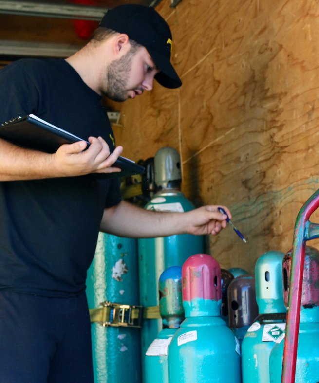 Un technicien faisant l'inventaire de bombonnes à gaz comprimé